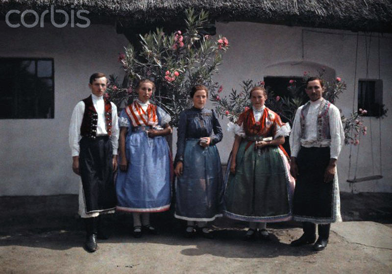 Farmers and girls stand before a flower-decorated house in Sopron, Hungary, January 1930.