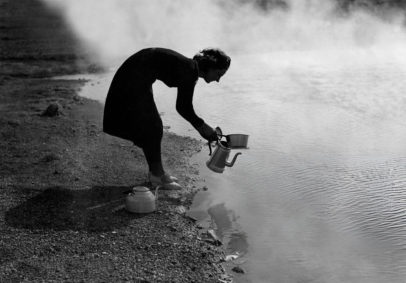 A woman getting hot water near a geyser in Iceland, 1935.