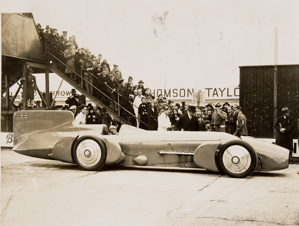 13 Sir Malcolm Campbell at the wheel of the Bluebird, with crowd, 1926 - 1936