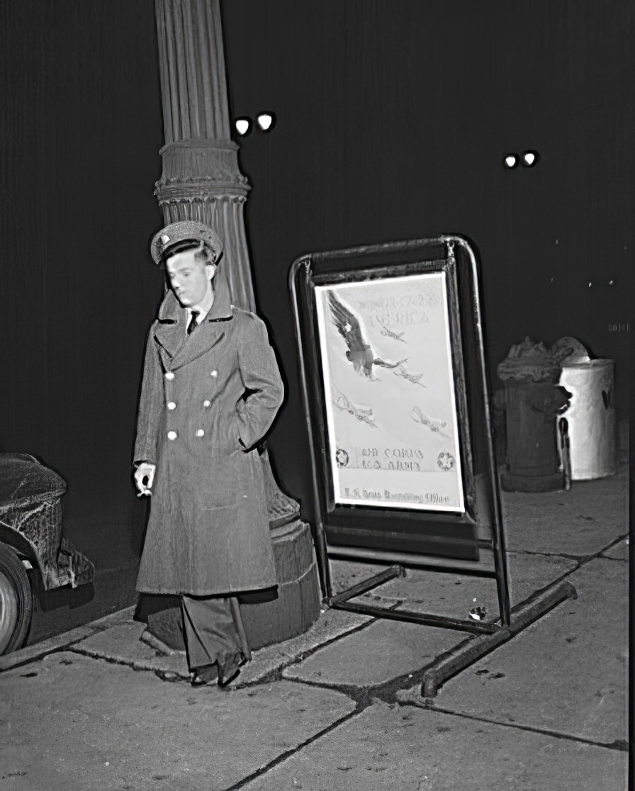 A lone soldier next to a recruitment sign on New Year's Eve in Detroit, 1942.