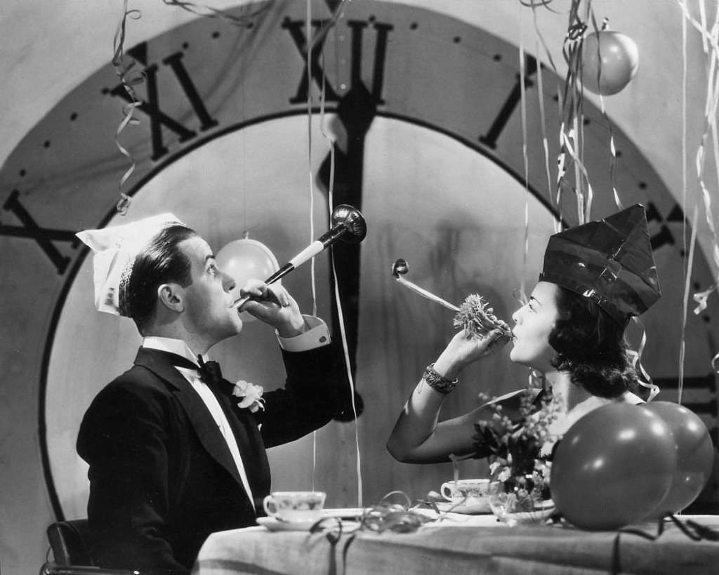 A couple celebrating New Year's Eve with party blowers and streamers, 1930.