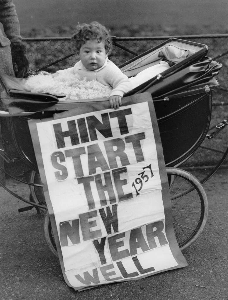 A baby with a New Year's Eve poster, 1937.