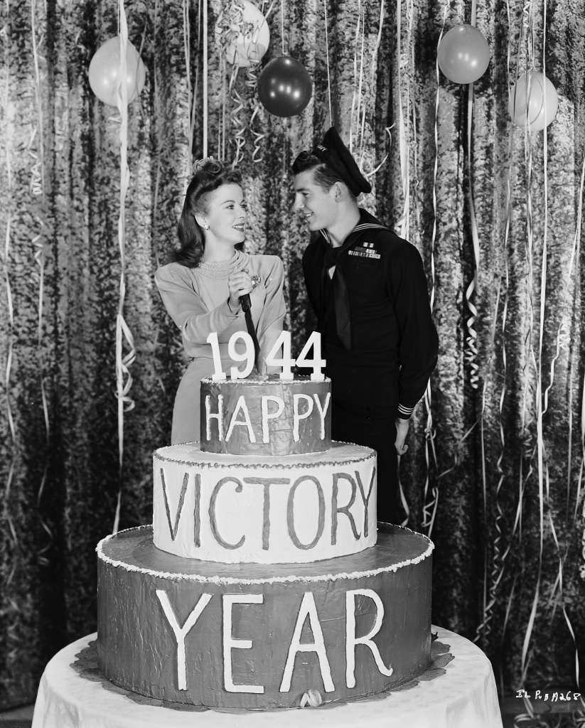 Ida Lupino cutting a "Happy Victory Year" cake, 1944.