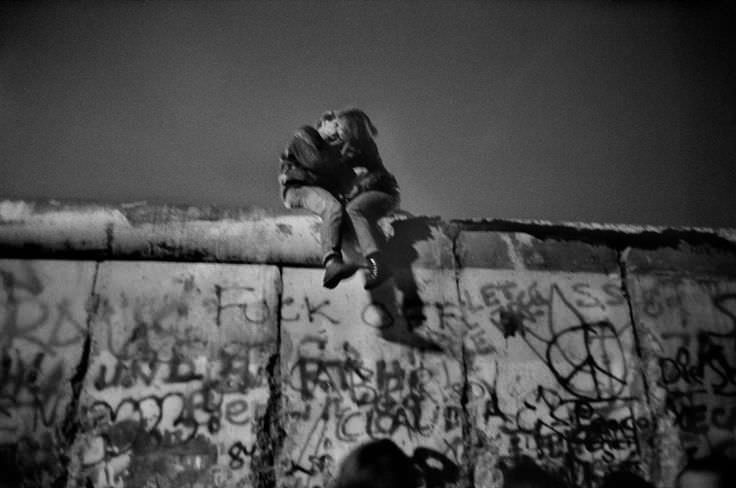 A German couple roll in the new year by kissing on the Berlin Wall, 1989