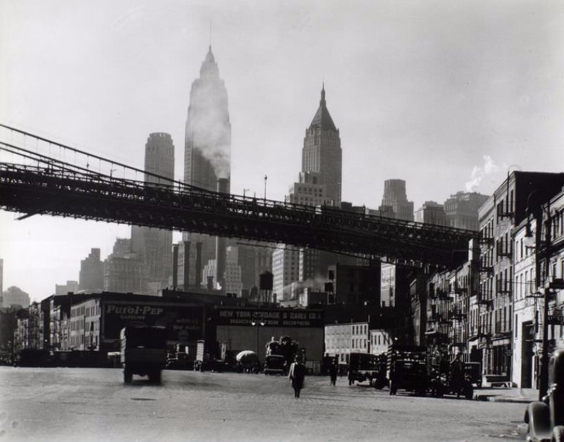 Waterfront, South Street, Manhattan. rooklyn Bridge span as it reaches land above South Street near James, tall buildings rise beyond.