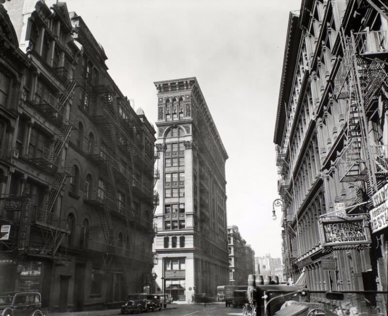 Broadway near Broome Street, Manhattan. Looking down Broadway, ornate Bank of Sicily Trust near center of image, sign for vegetarian restaurant, right, cars and trucks.