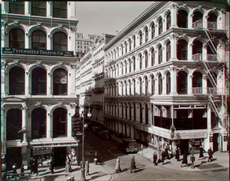 Looking into Thomas Street from a building across Broadway, white arched facades on both sides of Thomas, signs for men's clothing store, etc.