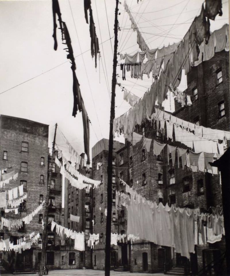 Court of first model tenement house in New York, 72nd Street and First Avenue, Manhattan. Poles in courtyard support lines loaded with laundry, apartment houses beyond.