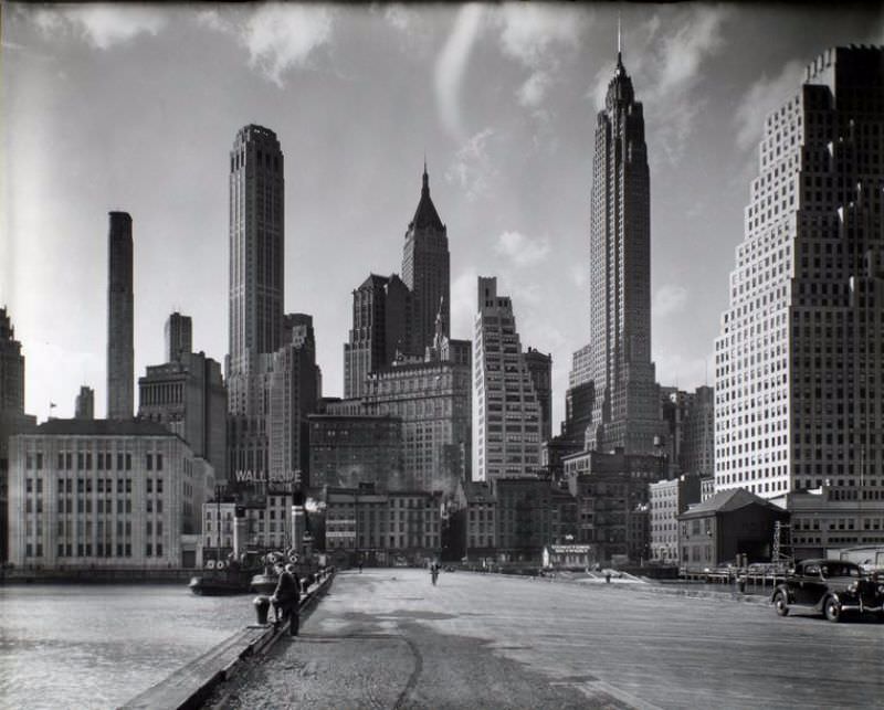 Looking from pier toward Manhattan, tugboats moored left, Downtown Skyport, right, skyscrapers in the background.