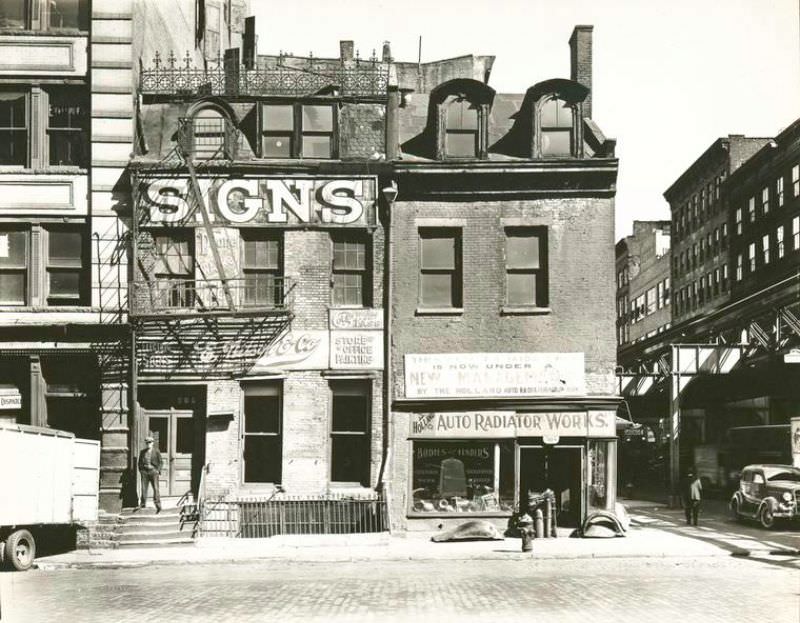 Broome Street, Nos. 504-506, Manhattan. Sign company with decorative ironwork along roof, auto radiator shop, in three-story buildings, the elevated railroad just visible at right.