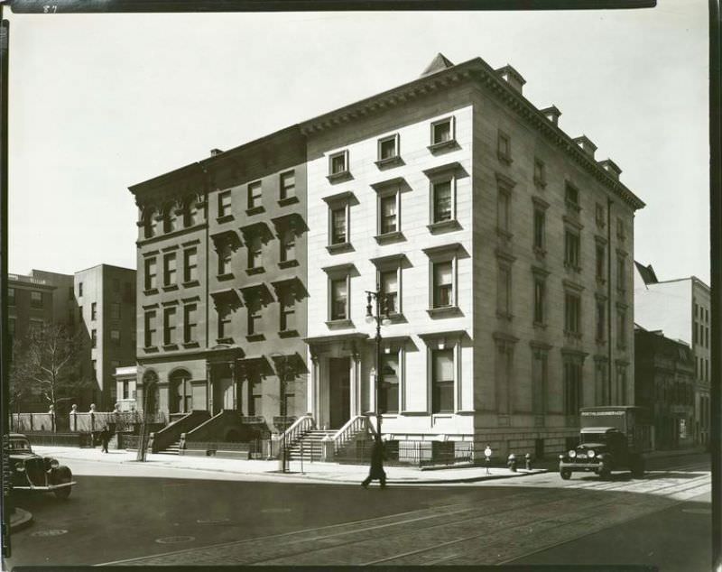 Three large row houses, including one of marble (#8) and traffic on Fifth Ave. and 8th St., and trolley tracks in 8th St.