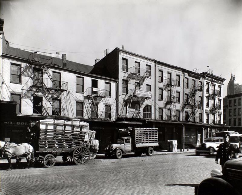 178-183 West Street, Manhattan. Wagon, truck in front of 3 and 4-story buildings with advertisements for furnished rooms, restaurants, hotel, policeman at right.