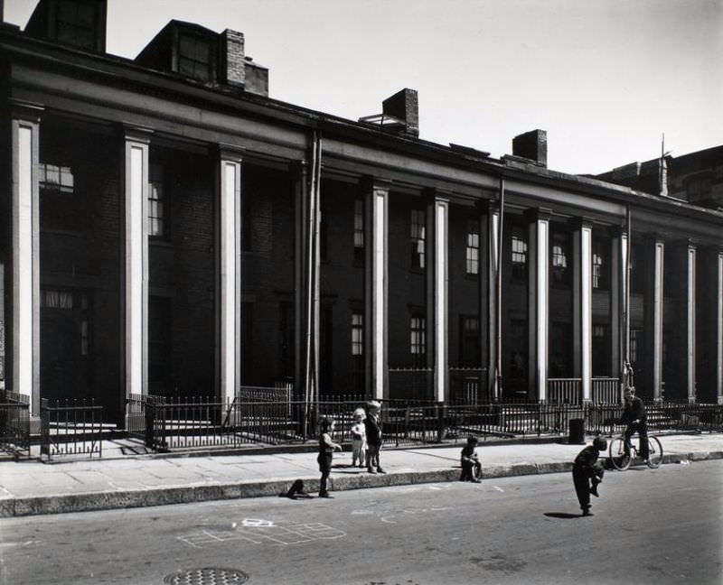 Willow Place, nos. 43-49, Brooklyn. Children play in front of brick row houses with Greek Revival colonnades.