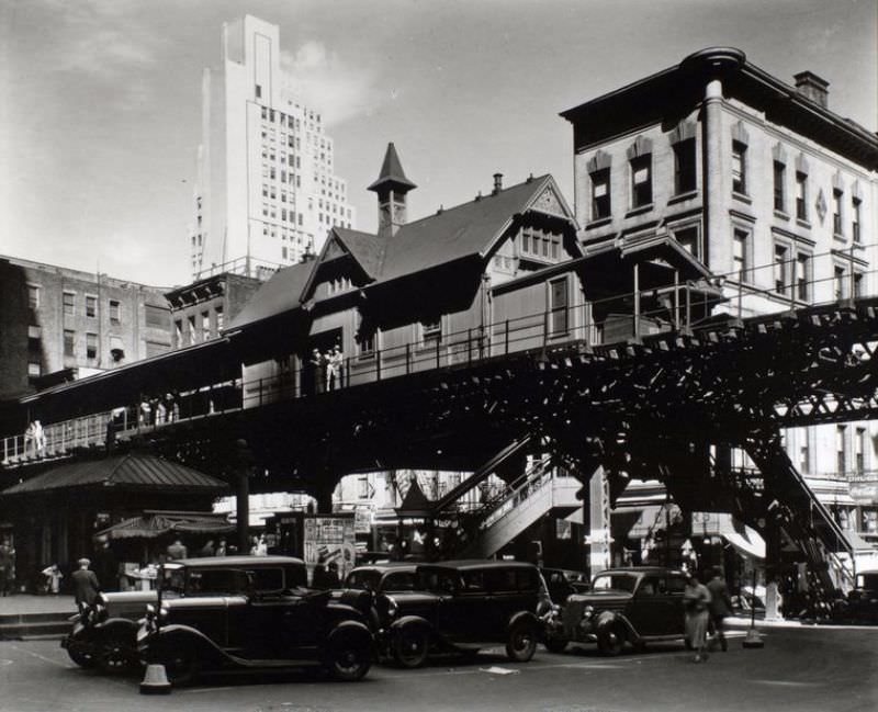 Elevated railroad station in Hanover Square in Lower Manhattan, cars below, buildings of various eras beyond.