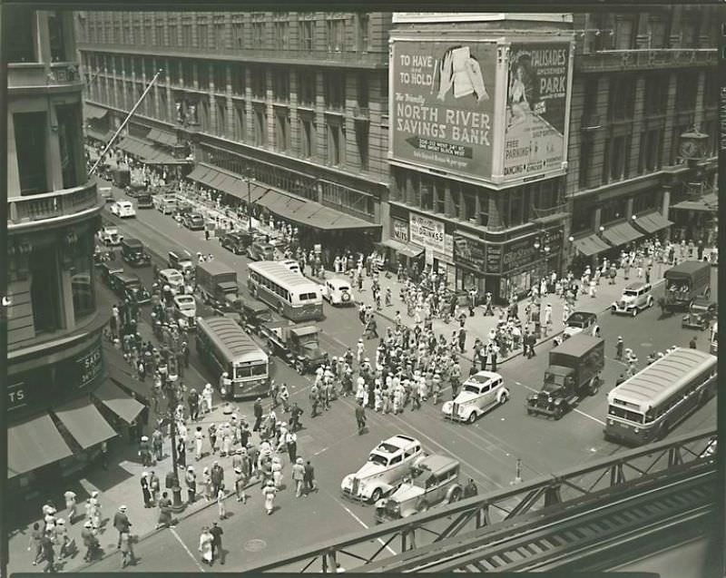 Herald Square. Looking down from 'el' station at intersection of 34th and Broadway; pedestrians, traffice, Macy's and billboards, Saks at 34th St.