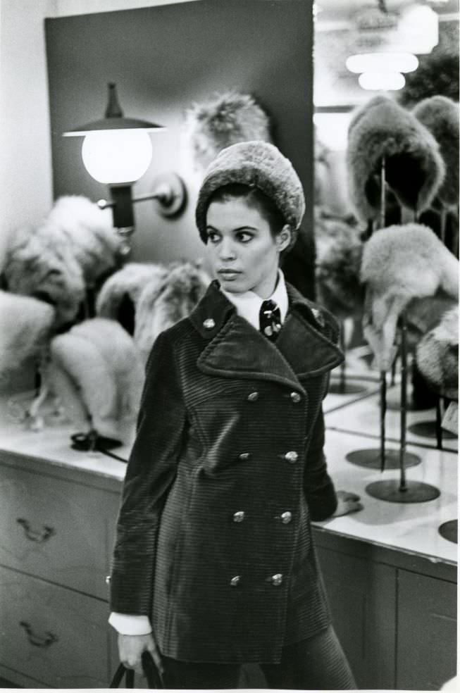 Woman in front of hat display.