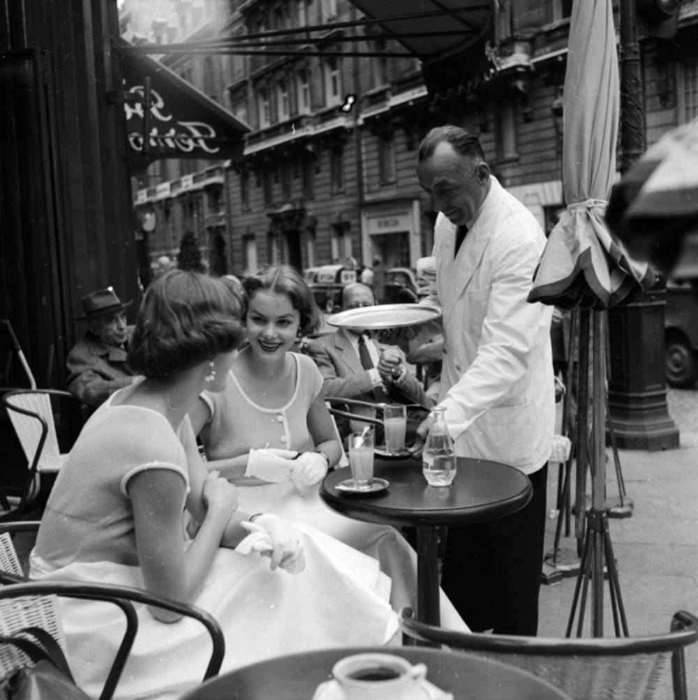 Twin sisters avoid eye contact with a waiter, 1955.