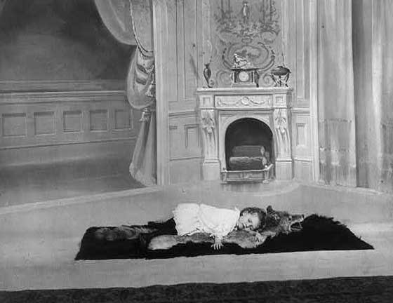 A little girl napping on a wolfskin rug, 1900.