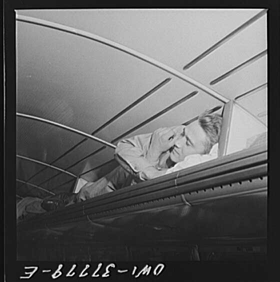 A soldier napping in a Greyhound bus luggage rack, 1943.