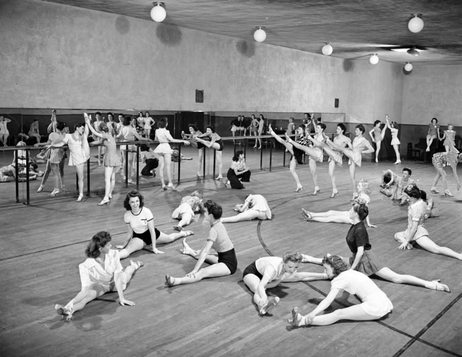 Rehearsal in 1942, at which the Rockettes stretch out their famous stems. Compared with modern-day rehearsals, where Rockettes wear identical black-spandex uniforms, all the girls here are in their own kicky skirts and character heels.