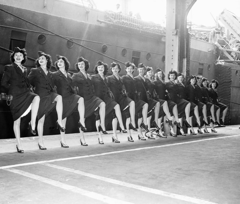 Ready to board a ship that will freight them to various U.S.O. performances during World War II, the Rockettes look the part in their military-inspired suits and miniature garrison hats, perched on their waves.