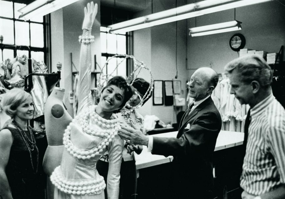 A beaming, space-suited Rockette gets her astronaut gear tweaked by nasa engineers—slash, the costume shop—backstage in the 60s.