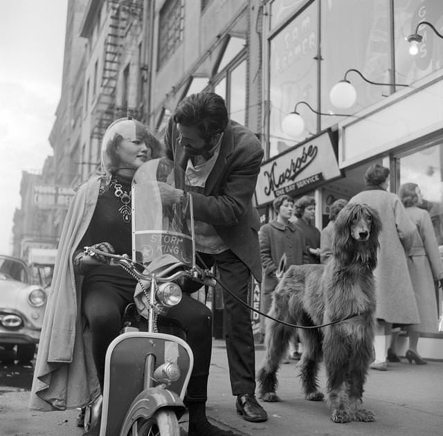 American jeweller, Sam Kramer helping one of his 'Space Girls' with her motorbike helmet on a Greenwich Village street, 1955.