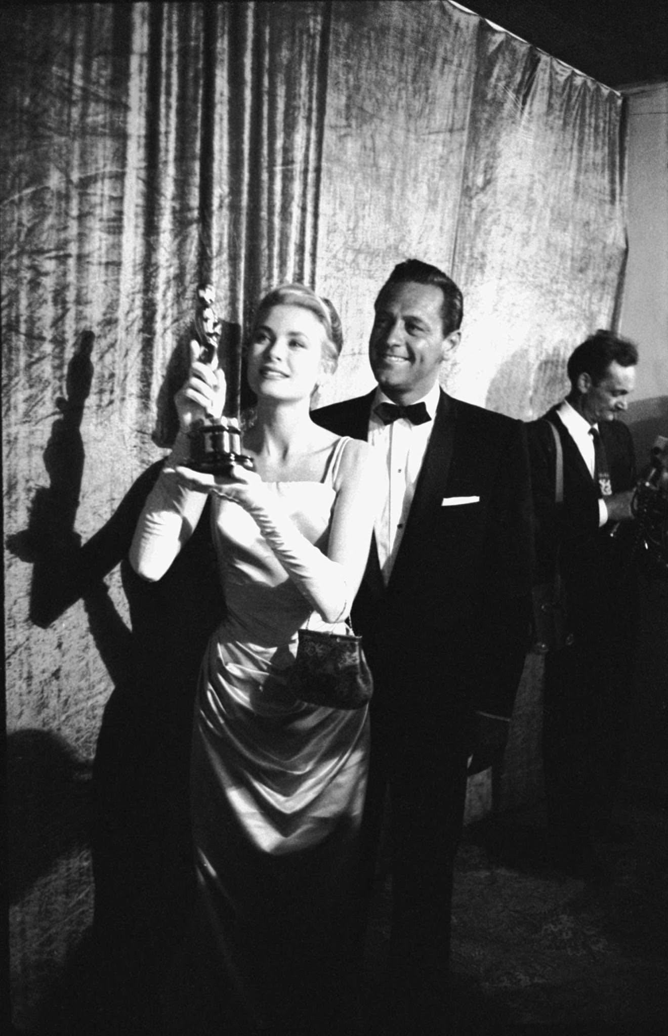 Grace Kelly with the Oscar she won for her role in The Country Girl, 1955. William Holden, her co-star in the movie, stands behind her.